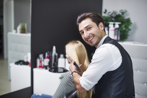 Portrait of smiling hairdresser at work stock photo