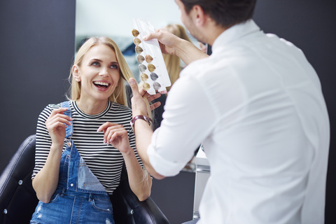 Hairdresser and happy woman at hair salon stock photo