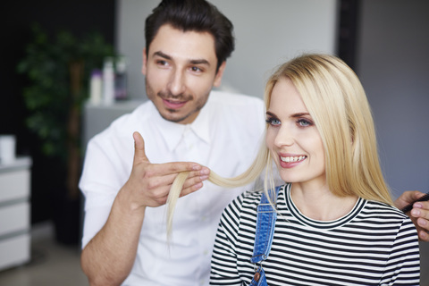 Hairdresser and smiling woman at hair salon stock photo