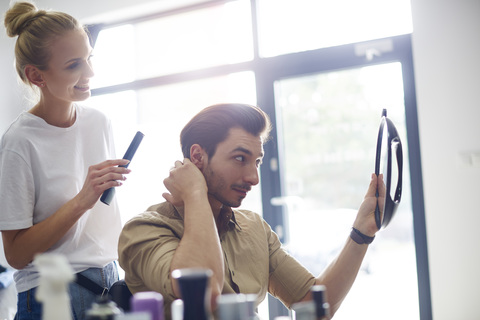 Mann überprüft seinen Haarschnitt beim Friseur, lizenzfreies Stockfoto