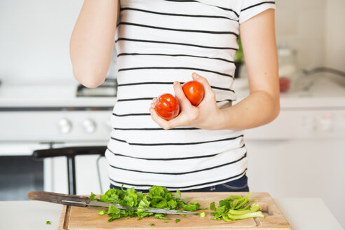 Mädchen steht in der Küche und hält Tomaten, Teilansicht - LVF06893