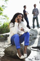 Lächelnde Frau auf einem Felsen sitzend - MASF06886