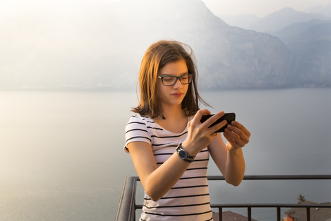 Italy, Brenzone, portait of girl taking selfie with smartphone on balcony stock photo