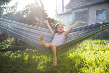 Portrait of happy little girl sitting on hammock in the garden - LVF06904