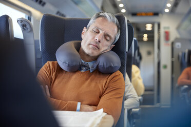 Tired businessman with neck pillow sleeping on passenger train - CAIF20228