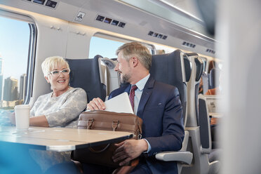 Businessman and businesswoman working, talking on passenger train - CAIF20237