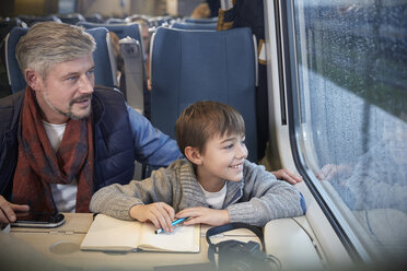 Vater und Sohn schauen aus dem Fenster eines Personenzugs - CAIF20241
