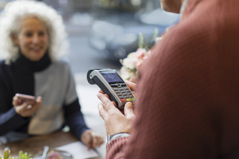 Kassierer mit Kreditkartenautomat, bereit für kontaktloses Bezahlen - CAIF20269