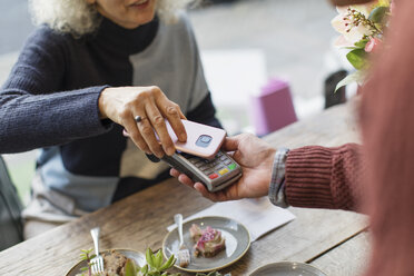 Woman with smart phone using contactless payment at cafe - CAIF20270