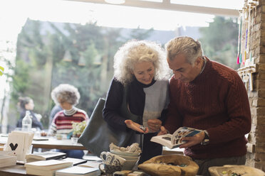 Älteres Paar betrachtet ein Buch im Laden - CAIF20277