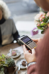 Kassierer mit Kreditkartenleser im Café - CAIF20279