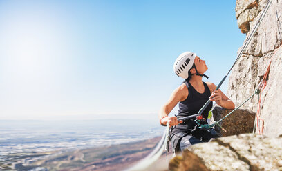 Weibliche Bergsteigerin, die ein Seil hält und nach oben schaut - CAIF20287