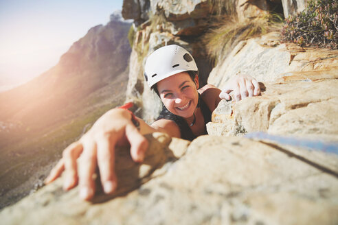 Porträt eines lächelnden, selbstbewussten Bergsteigers, der nach einem Felsen greift - CAIF20290