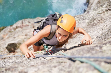 Focused, determined female rock climber scaling rock - CAIF20295