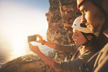 Kletterer mit Fotohandy beim Fotografieren des Ozeans - CAIF20297