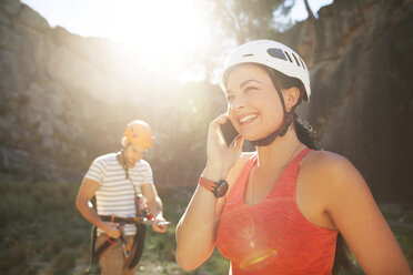 Lächelnde Bergsteigerin, die mit ihrem Smartphone telefoniert - CAIF20302