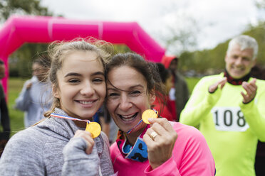 Porträt einer lächelnden, selbstbewussten Mutter und einer Tochter, die beim Wohltätigkeitslauf ihre Medaillen zeigen - CAIF20315