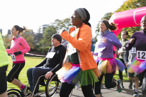 Läuferin im Tutu läuft in der Menge beim Wohltätigkeitslauf im sonnigen Park - CAIF20317