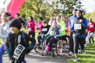 Läufer und Menschen im Rollstuhl beim Wohltätigkeitslauf im Park - CAIF20331