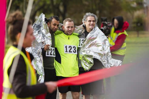 Männliche Marathonläufer, eingewickelt in eine Wärmedecke an der Ziellinie - CAIF20334