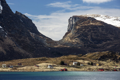 Berge über abgelegenen Häusern am Meer, Krystad, Lofoten, Norwegen - CAIF20344