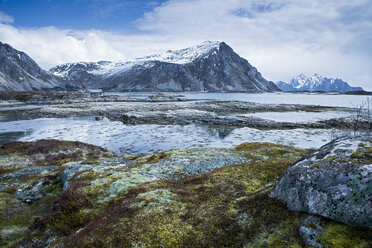 Moosbewachsene Felsen inmitten eines abgelegenen Fjords und von Bergen, Langraget, Lofoten, Norwegen - CAIF20348