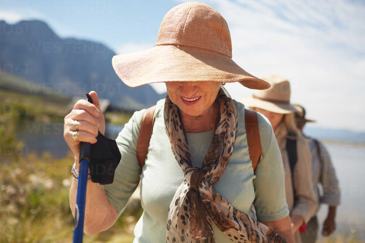 Active senior woman in sun hat hiking stock photo