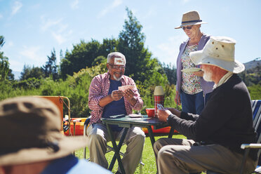 Verspielte, aktive Seniorenfreunde spielen Karten auf einem sonnigen Sommercampingplatz - CAIF20375