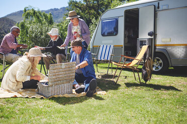 Aktive ältere Freunde genießen ein Picknick vor dem Wohnmobil auf einem sonnigen Sommercampingplatz - CAIF20379