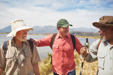 Aktive ältere Männerfreunde beim Wandern am sonnigen Seeufer - CAIF20387