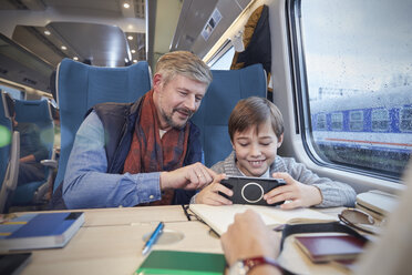 Vater und Sohn benutzen ein Smartphone im Personenzug - CAIF20406