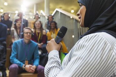Lächelnde Geschäftsfrau im Hidschab, die mit einem Mikrofon zum Publikum spricht - CAIF20416