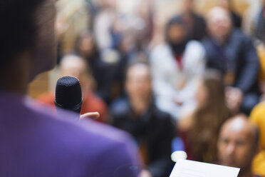 Geschäftsmann mit Mikrofon spricht zu Konferenzteilnehmern - CAIF20446