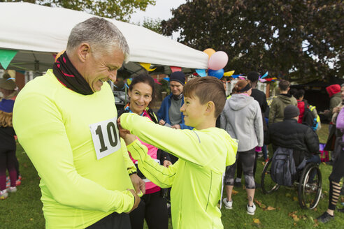 Familienläufer stecken ihre Marathon-Startnummern an und bereiten sich auf einen Wohltätigkeitslauf im Park vor - CAIF20467