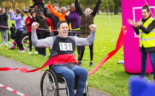 Begeisterter Mann im Rollstuhl überquert die Ziellinie bei einem Wohltätigkeitsrennen im Park - CAIF20484