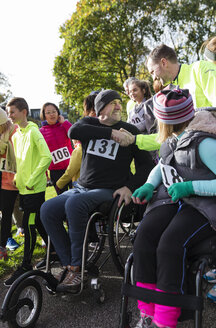 Mann im Rollstuhl schüttelt beim Wohltätigkeitslauf einem Läufer in der Menge die Hand - CAIF20493