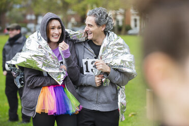 Glückliches Läuferpaar in Thermodecke eingewickelt beim Wohltätigkeitslauf im Park - CAIF20495