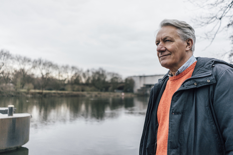 Älterer Mann am Flussufer mit Blick zur Seite, lizenzfreies Stockfoto