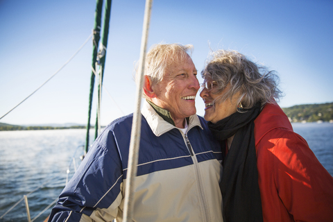 Fröhliches älteres Paar in Yacht auf dem Meer gegen klaren Himmel, lizenzfreies Stockfoto