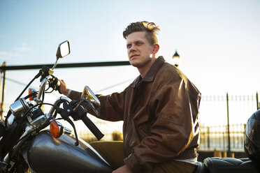 Thoughtful man sitting on motorcycle against sky - CAVF48197