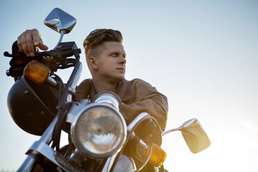 Niedriger Blickwinkel auf einen Mann, der auf einem Motorrad sitzt, gegen einen klaren Himmel - CAVF48201