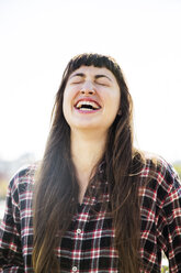 Cheerful woman laughing against clear sky - CAVF48227