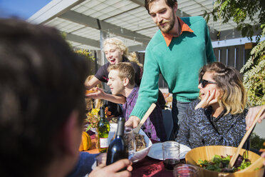 Mann serviert Freunden während einer Gartenparty Essen - CAVF48235