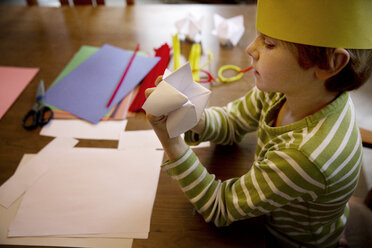 Hohe Winkel Ansicht des Jungen machen Origami Wahrsagerin am Tisch - CAVF48270