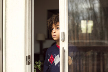 Thoughtful boy looking through window at home - CAVF48279