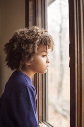 Side view of thoughtful boy looking through window at home - CAVF48283