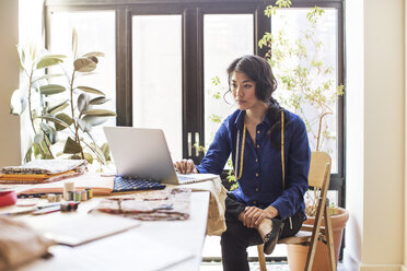 Design professional using laptop computer at desk in office - CAVF48332