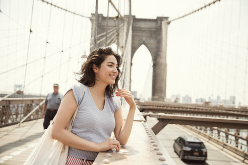 Lächelnde Frau auf der Brooklyn Bridge in der Stadt - CAVF48394
