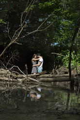 Romantisches Paar, das sich umarmt, während es im Wald steht - CAVF48423