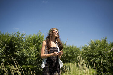 Glückliche Frau mit Diadem auf einem Feld vor blauem Himmel - CAVF48435